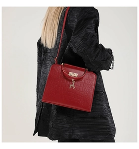 Model wearing a red crocodile pattern handbag with gold deer charm and handle