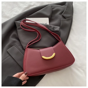 Close-up of matte wine red leather shoulder bag with iconic golden metal buckle detail