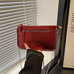Metallic red crossbody bag with silver bead trim and chain strap in a stylish setting