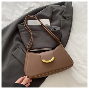 Detail of caramel leather shoulder bag featuring a unique half-moon golden metal clasp