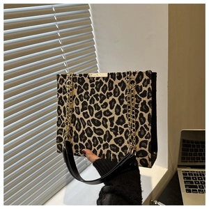Détail d'un sac cabas léopard avec des chaînes dorées et une poignée en cuir noir