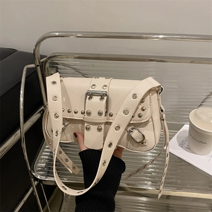 Sac bandoulière blanc cassé avec œillets argentés et boucle dans un décor urbain chic