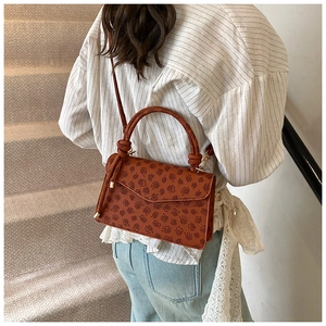 Detailed back view of a vintage brown crossbody bag with embossed floral patterns on stairs