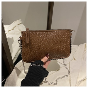 Close-up of brown woven texture and silver chain on a trendy crossbody square bag