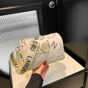 Sac cylindrique blanc moderne avec lettres imprimées et large bandoulière dans une pièce