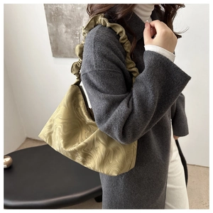 Gros plan du sac en satin vert avec détail de bandoulière à volants et plis élégants