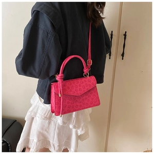 Detailed view of rose red square bag featuring embossed clover patterns and top handle