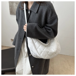 Détail d'un sac demi-lune blanc matelassé porté avec un manteau en laine gris élégant