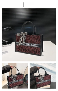 Détail du sac cabas imprimé léopard rouge avec anses en cuir noir et nœud fantaisie