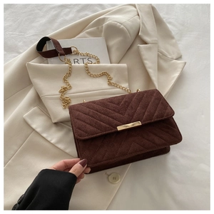 Detail of dark brown suede crossbody bag with V-quilted texture and gold metal chain