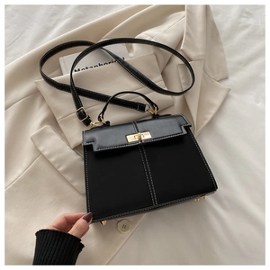 Détail du sac style Kelly noir avec surpiqûres blanches et fermoir rotatif doré