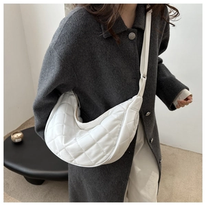 Gros plan d'un sac bandoulière blanc matelassé en forme de lune avec sangle réglable