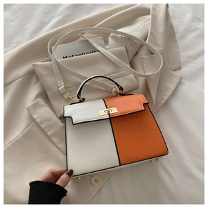 Détails du sac bicolore avec fermoir rotatif doré et pieds sur un blazer souple