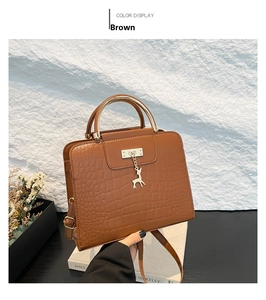 Brown crocodile embossed leather handbag with gold circular handle and deer pendant charm