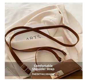 Close-up of brown suede crossbody bag with gold buckle on a white blazer background