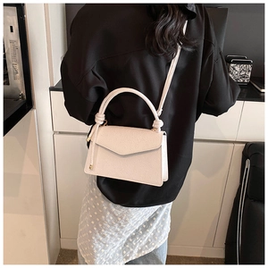 Detail of white embossed leather handbag with envelope flap worn by model