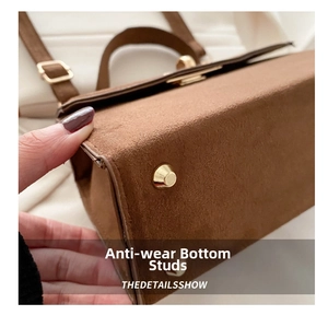 Macro detail of golden bottom protective studs on brown frosted suede handbag