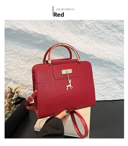 Detail of red crocodile texture handbag with golden deer charm and metal handle