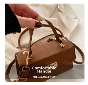 Detail of a brown suede handbag with a reinforced handle and gold metal twist lock closure