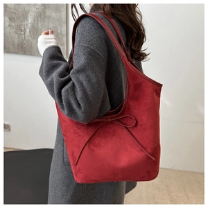 Close-up of a large vintage red frosted tote bag with a bow detail on a grey wool coat