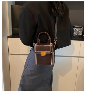 Detail of vintage brown leather handbag with pearl trim and gold clasp worn cross-body