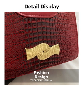Detail of dark red crocodile embossed leather with a wavy golden metallic buckle