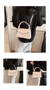 Detail of cream white handbag with embossed texture and circular knotted handle detail