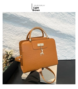 Detail of light brown crocodile-embossed purse with golden handle and deer charm