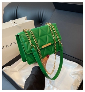 Detail of green quilted crossbody bag with golden metal lock and chain strap