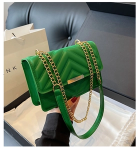 Detail of green V-quilted shoulder bag featuring a gold chain strap and metal lock closure