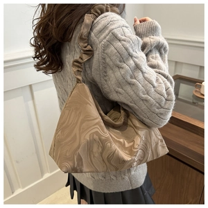 Détail du sac bandoulière avec texture marbrée brune et bandoulière à volants en intérieur