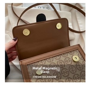 Close-up of retro monogram handbag with dual golden magnetic buckles and leather trim