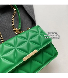 Detail of green quilted handbag with geometric triangular stitching and gold metal buckle