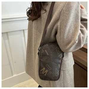 Detail of a brown lychee pattern crossbody bag with letter print on a wool coat