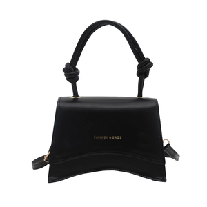 Classic black trapeze handbag with knot handle and curved base in minimalist design