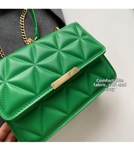 Detail of bright green quilted PU leather handbag with gold rectangular clasp and chain
