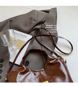 Detailed view of the smooth long strap and glossy brown leather of this tote bag