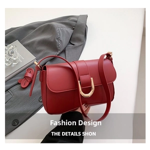 Close-up of vintage burgundy handbag with gold U-shaped buckle on a stylish office background