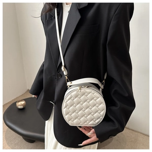 Close-up of white round crossbody bag with quilted texture shown on a model