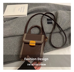 Detail showing the dark brown polished leather texture and gold metal buckle on a handbag