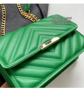 Close-up of green chevron quilted shoulder bag with gold chain strap and metal lock
