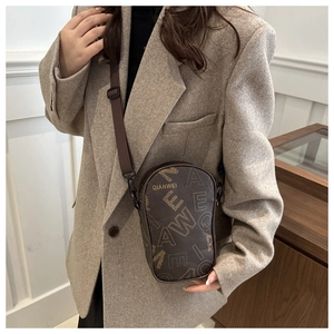 Close-up of a brown leather mini crossbody bag with letter print and wide strap