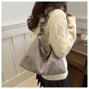 Close-up of pleated shoulder bag with marble texture and ruffled strap on a model