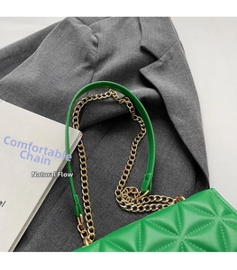 Detail of green quilted handbag featuring a sleek metal chain and matching leather shoulder pad