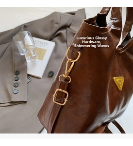 Detail of vintage oil wax leather bag with golden buckle and side triangle metal logo