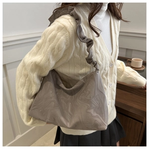 Detail of taupe cloud-style hobo bag featuring marble texture and ruffled shoulder strap