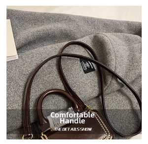 Detailed close-up of a vintage dark brown leather mini handbag with sturdy round handle