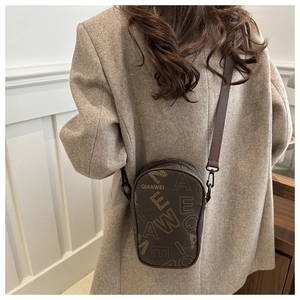 Detail view of brown PU leather crossbody bag with vintage letter print on a model