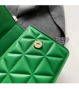 Detail of green quilted crossbody bag with golden round magnetic snap closure and texture