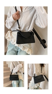 Detail of black faux leather crossbody bag featuring embossed patterns and knotted handle